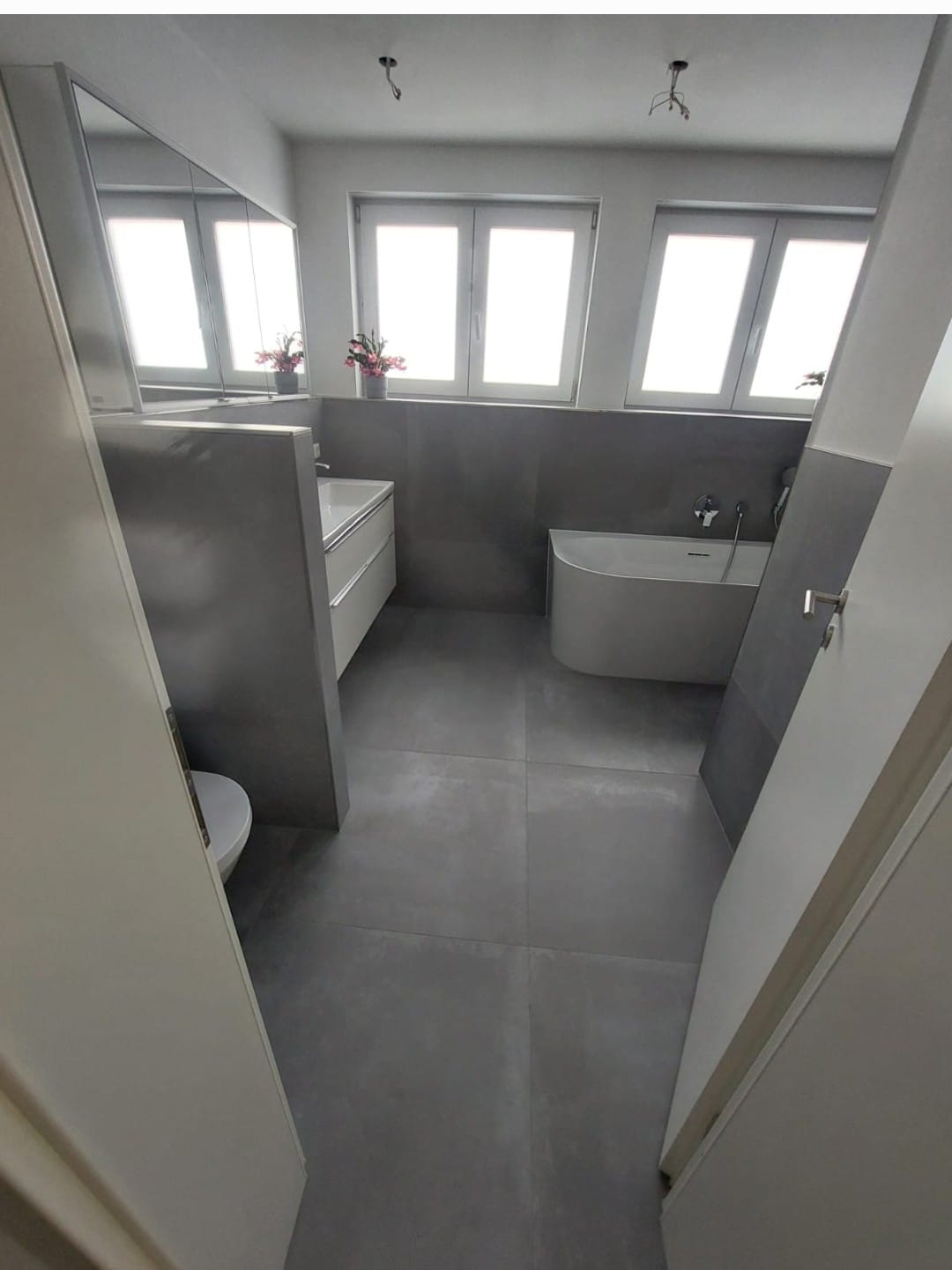 Badsanierung mit eleganter freistehender Badewanne und großformatigen grauen Fliesen in Stuttgart – modernes Badezimmerdesign.